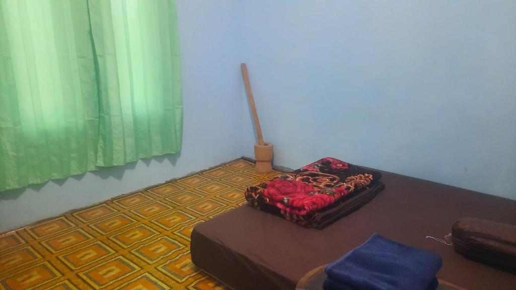 Zimmer mit einem Tisch, einem Bett und einem Fenster in der Unterkunft Wisma PO'ONG in Ruteng