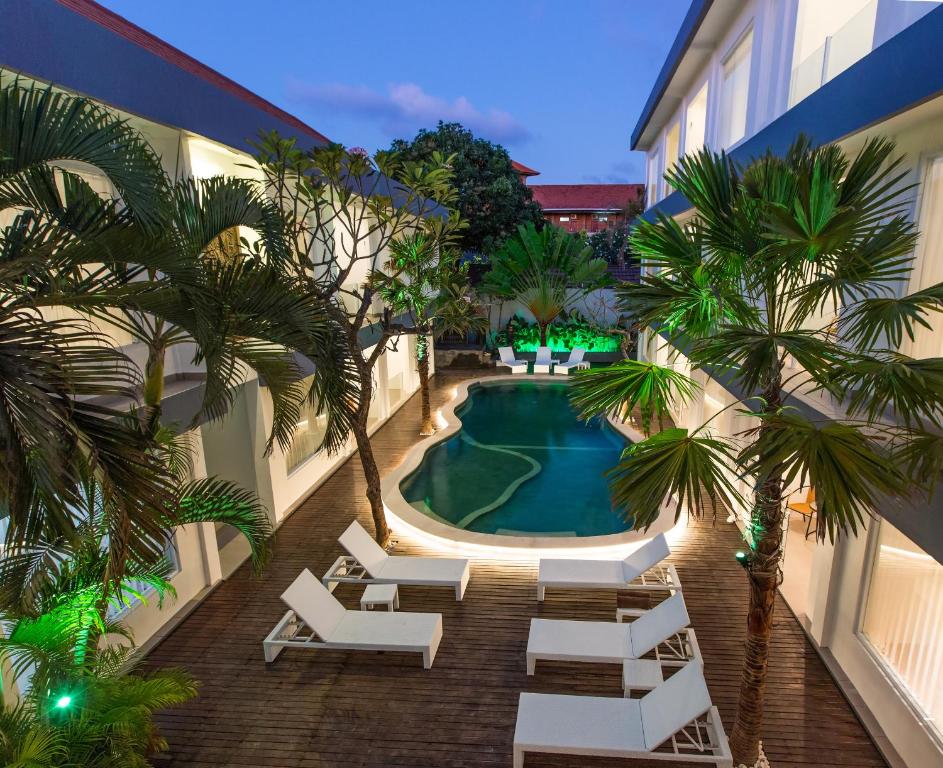 an overhead view of a swimming pool with chairs and palm trees at Coast Boutique Hotel in Kuta