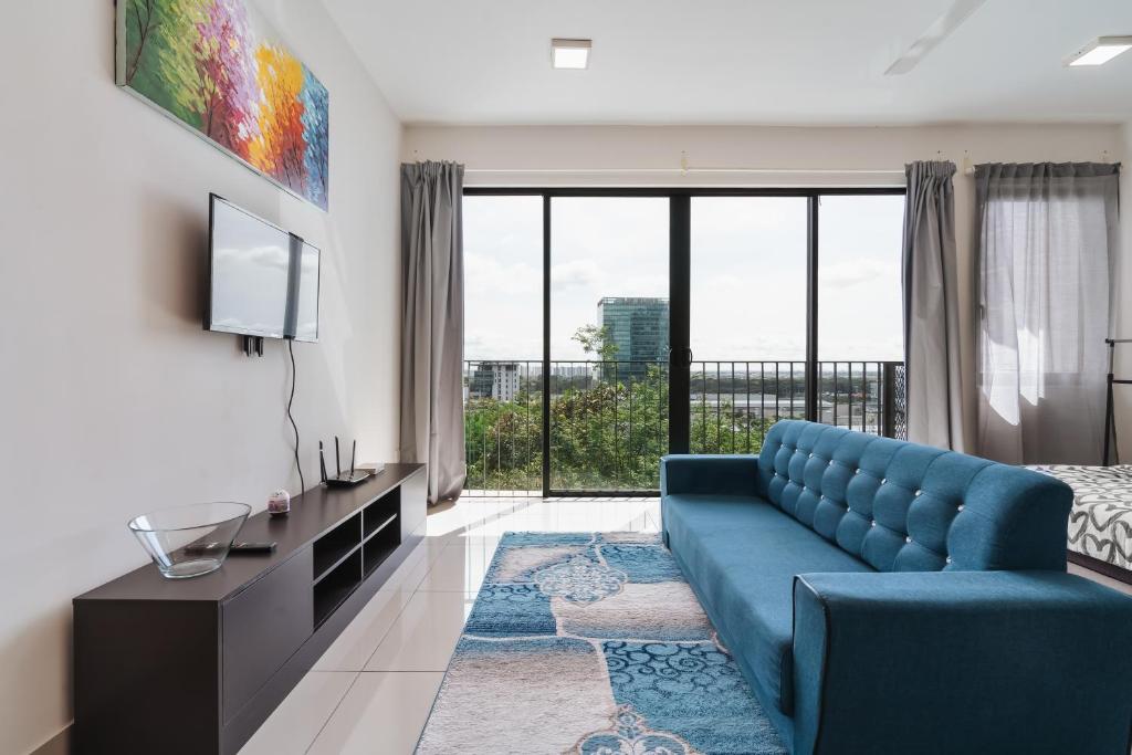 a living room with a blue couch and a large window at NETFLIX STUDIO @ TREFOIL SETIA CITY in Setia Alam