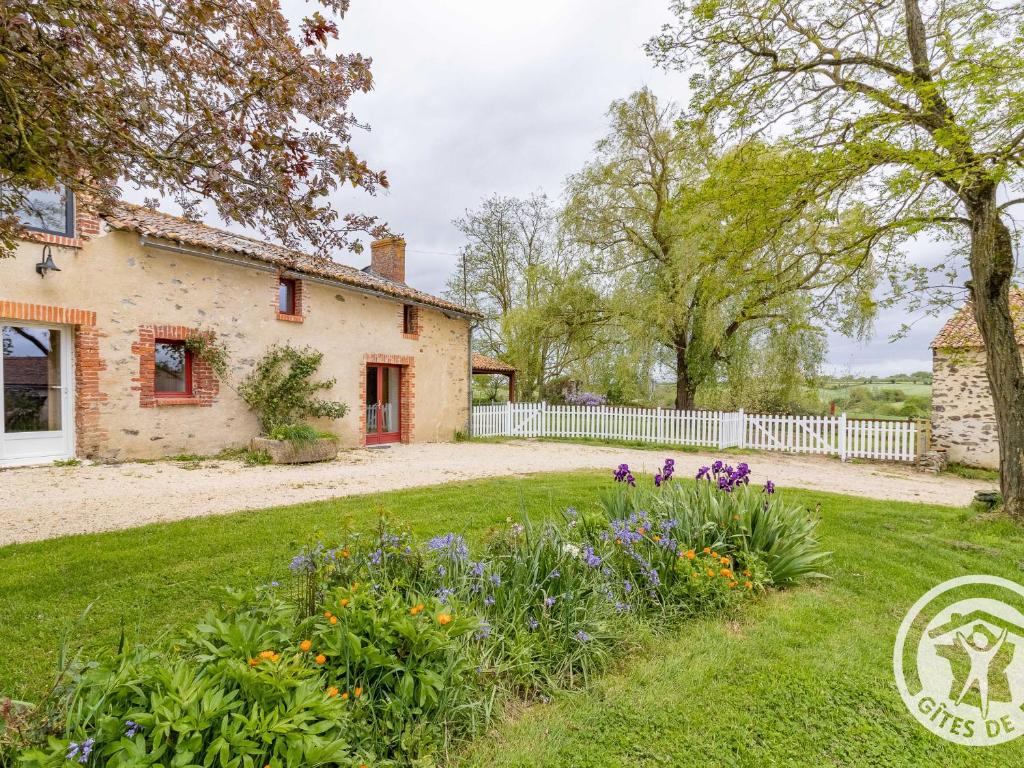 ein altes Steinhaus mit einem weißen Zaun und Blumen in der Unterkunft Gîte confortable 2 chambres avec jardin, animaux admis, Wifi, parking - FR-1-622-80 in Vihiers