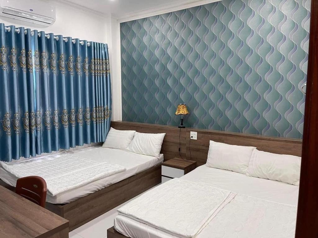 a bedroom with two beds and a blue wall at Kim Ngân Motel in Chau Doc