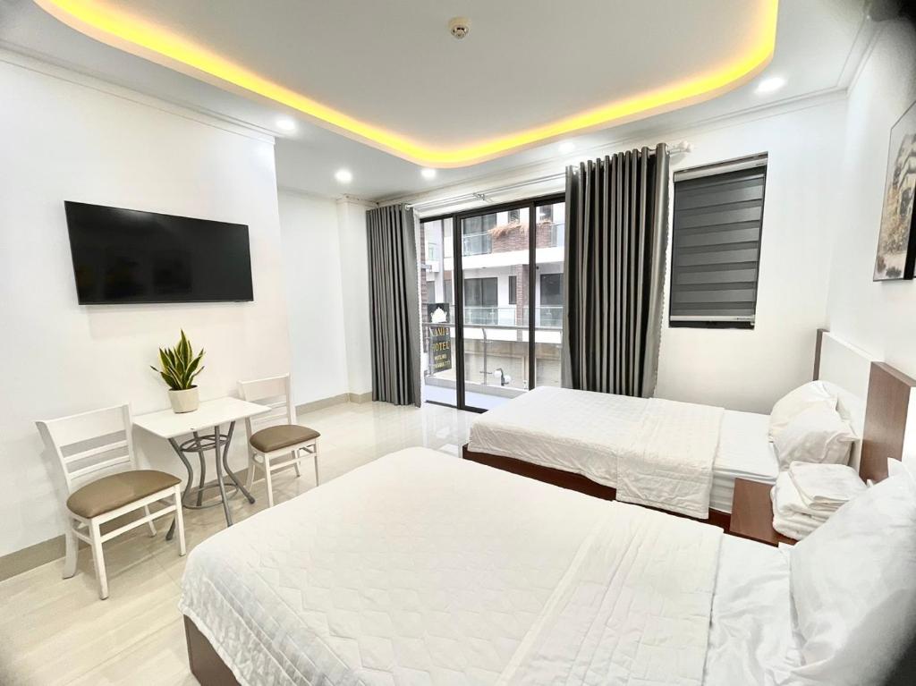 Habitación de hotel con 2 camas, mesa y sillas en KAMI HOTEL en Phan Rang