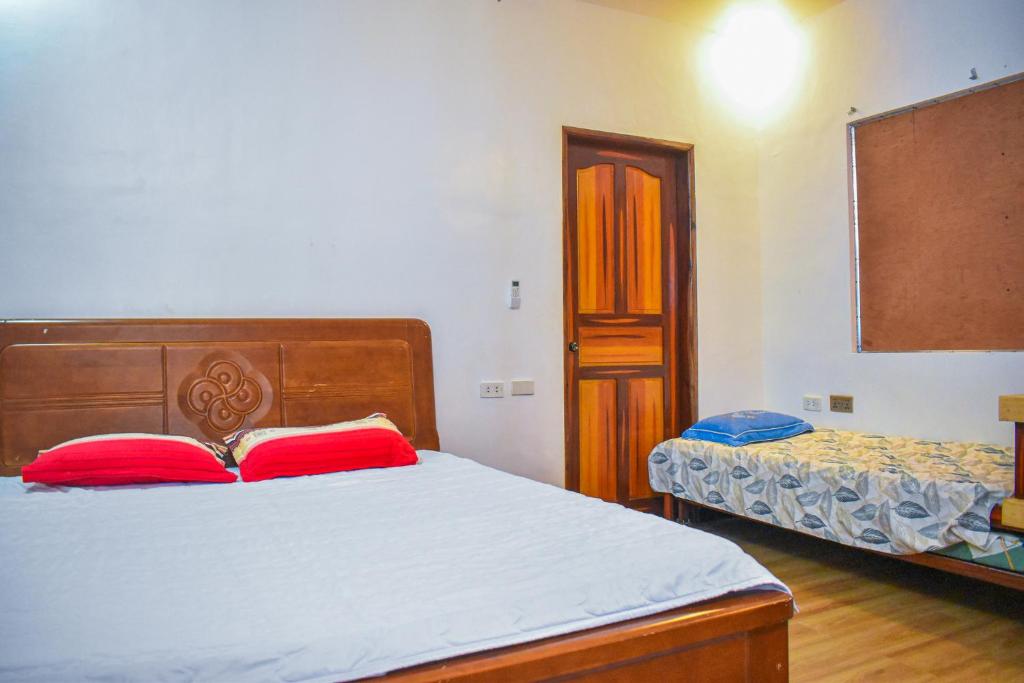 1 dormitorio con 1 cama con 2 almohadas rojas en Casa de Madera The Wooden House en Cabuyao