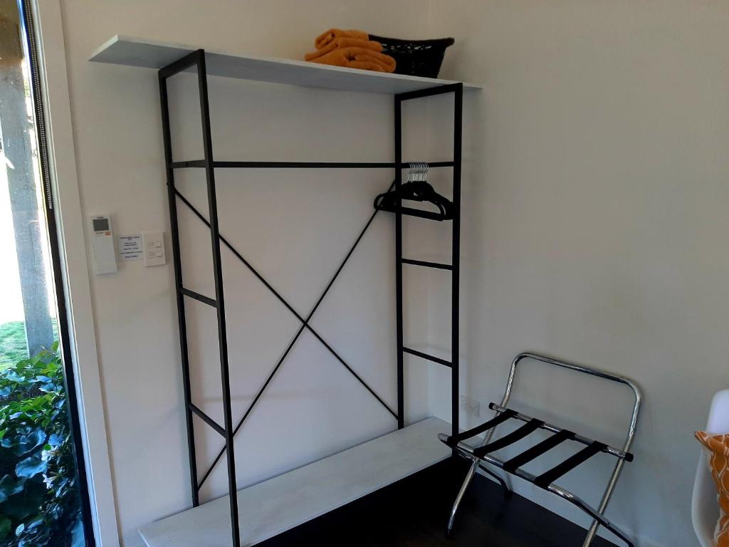 a shelf in the corner of a room with a chair at Tree View Studio in Tauranga
