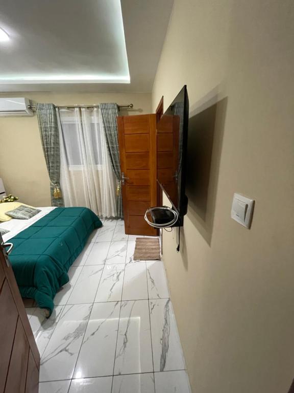 een slaapkamer met een bed en een televisie. bij Residence Therese La Grâce in Douala