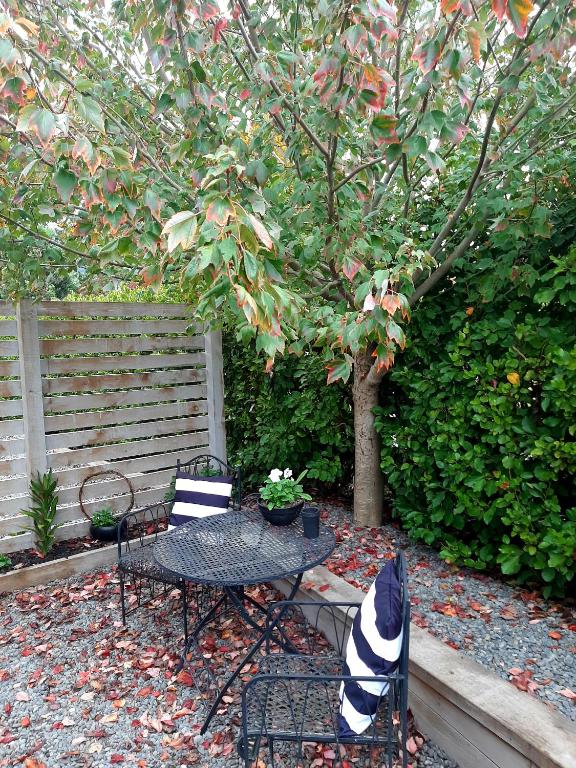 a patio with a table and chairs and a tree at Tree View Studio in Tauranga