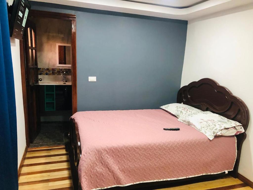 a bedroom with a bed with a pink bedspread at CASA DE CAMPO HOSPEDAJe in Ambato