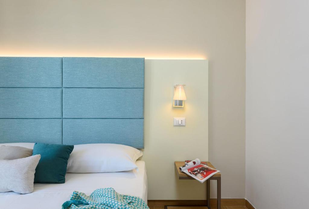 a bedroom with a bed with a blue headboard at Andromeda Hotel in San Vito lo Capo