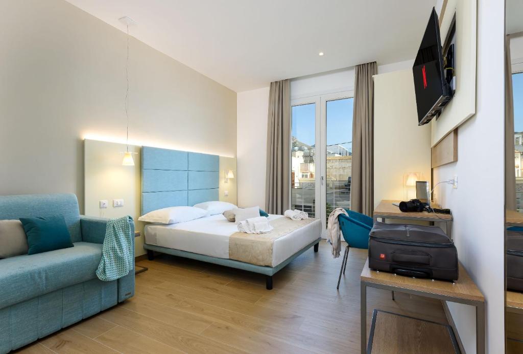 a hotel room with a bed and a couch at Andromeda Hotel in San Vito lo Capo