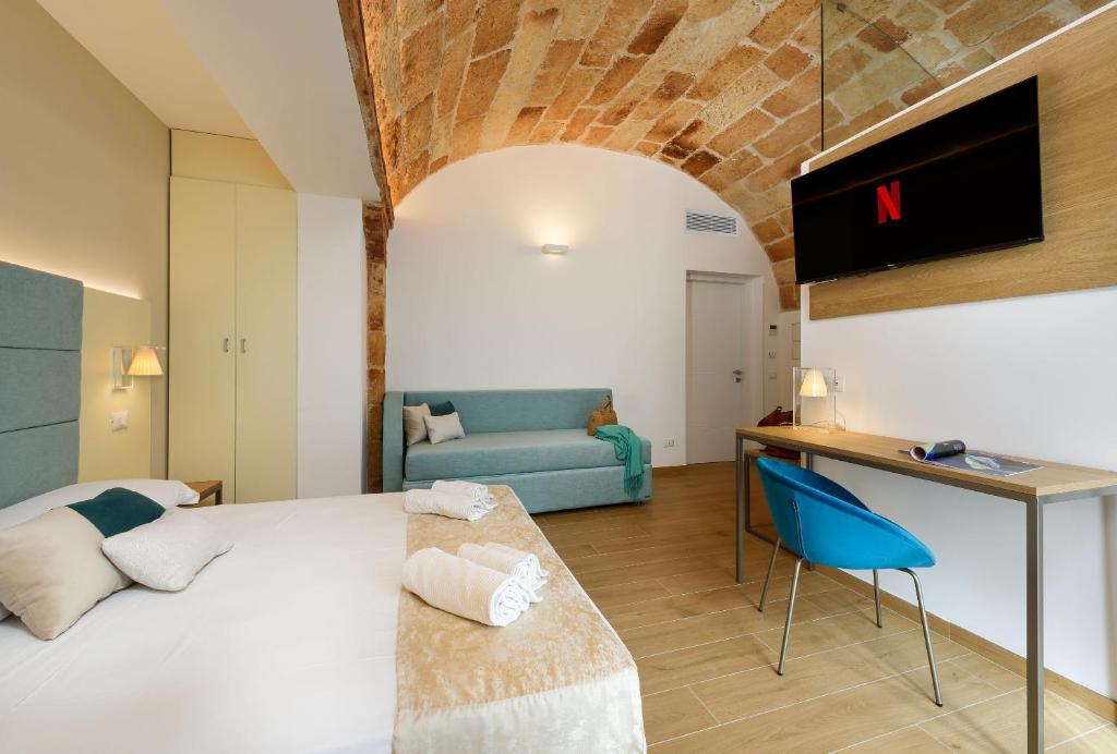a bedroom with a large bed and a blue couch at Andromeda Hotel in San Vito lo Capo