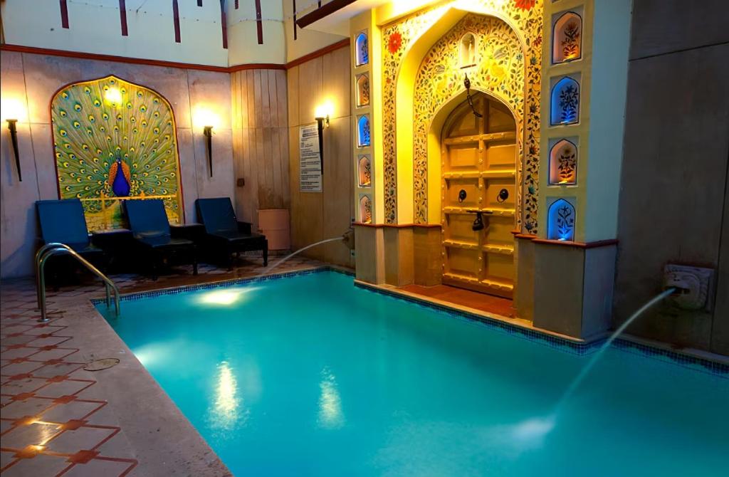 uma piscina com água azul num edifício em Umaid Mahal - A Heritage Style Boutique Hotel em Jaipur