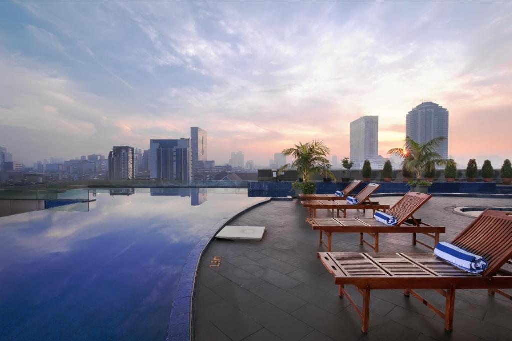 a swimming pool with chairs and a city skyline at Merlynn Park Hotel in Jakarta