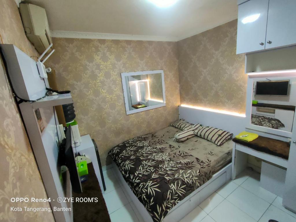 a small room with a bed and a mirror at Zye Rooms apartemen in Teko