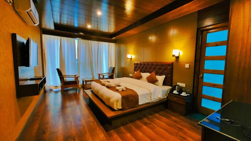 Vista Resort, Manali - centrally Heated & Air cooled luxury rooms في مانالي: غرفة نوم بسرير وطاولة وكراسي