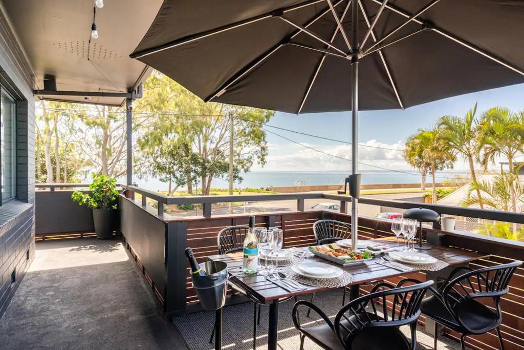 einen Tisch und Stühle auf einem Balkon mit Sonnenschirm in der Unterkunft 549 Luxury Apartments in Hervey Bay