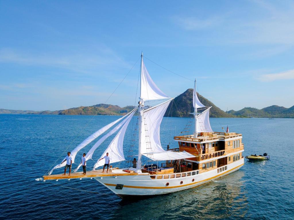 a large boat with three men standing on it in the water at DAV Travels in Labuan Bajo