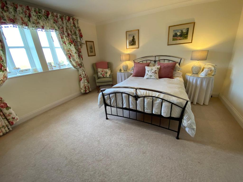 a bedroom with a bed and two tables and a window at Lower Farm Cottage in Beaminster