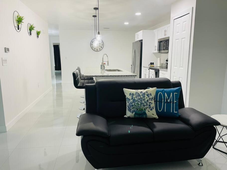 a black couch in a living room with a kitchen at White house 2 in Lehigh Acres