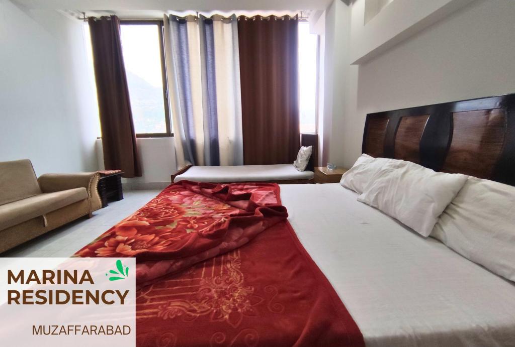 Cette chambre comprend un lit avec une couverture rouge. dans l'établissement Marina Residency, à Muzaffarabad