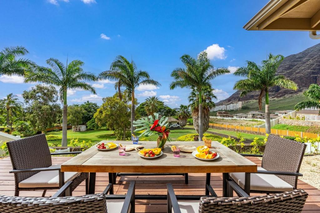 a table with plates of food on a patio with palm trees at Aloha Breeze by AvantStay Ocean View Near Beach in Waianae