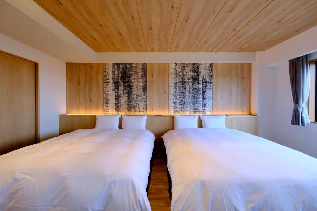 Kiki Shiretoko Natural Resort في شاري: سريرين في غرفة بسقوف خشبية