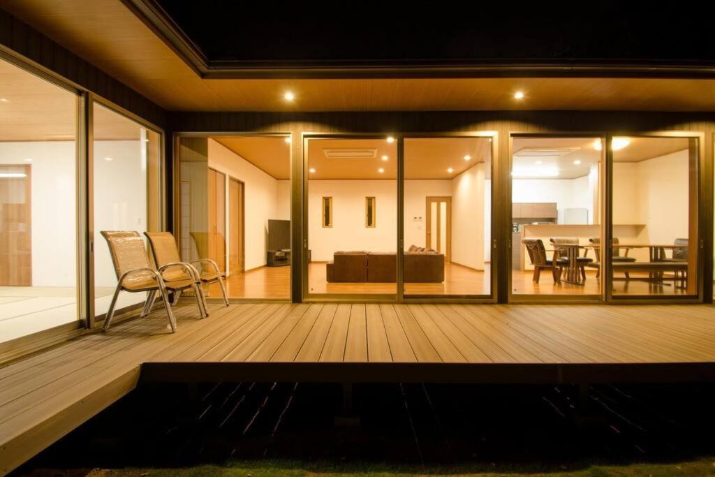 a large deck with a couch and a table at 森の空気を感じる宿泊 露天風呂 Wi-Fi 最大20名様 in Shima