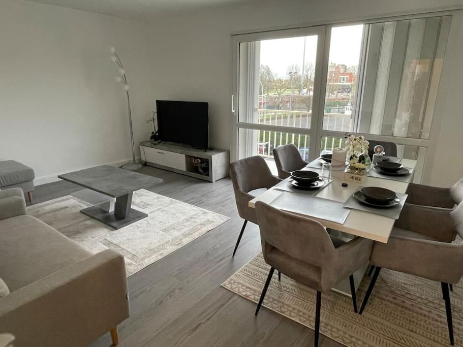 uma sala de estar com uma mesa e cadeiras e uma televisão em Appartement champs de course, proche paris centre em Eaubonne