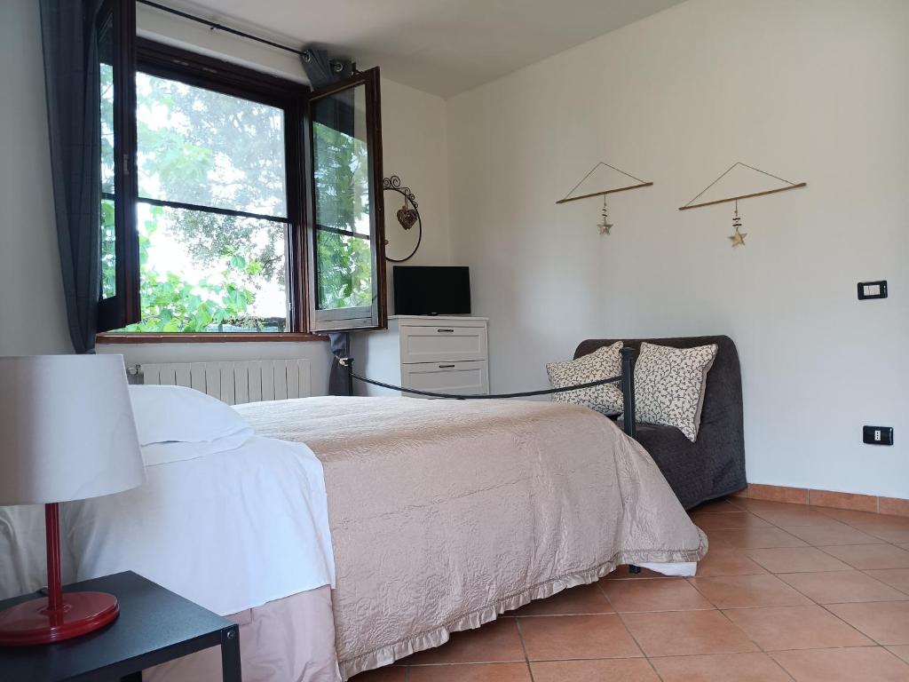 a bedroom with a bed and a tv and a window at Agriturismo Le Villette di Cate in Alberese
