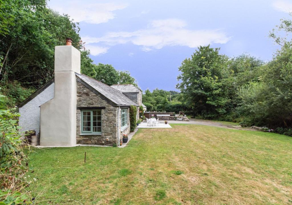 an old stone house with a grass yard at Troutstream in Saint Tudy