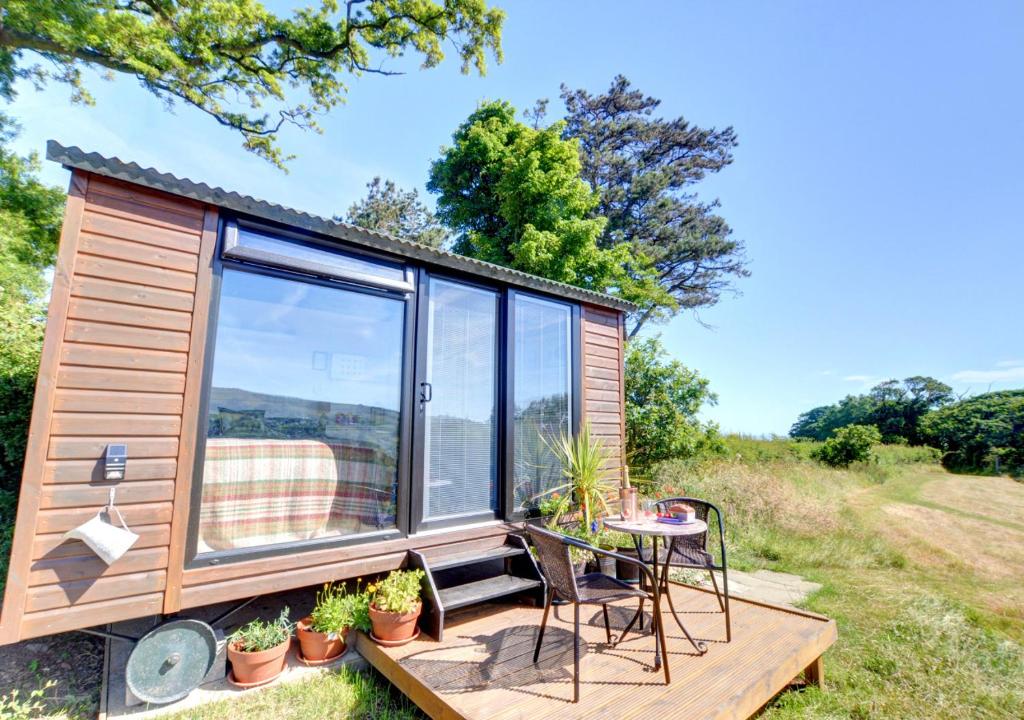 a tiny house with a deck with a table and chairs at Shepherds Hut at Ridge Hall in Staithes