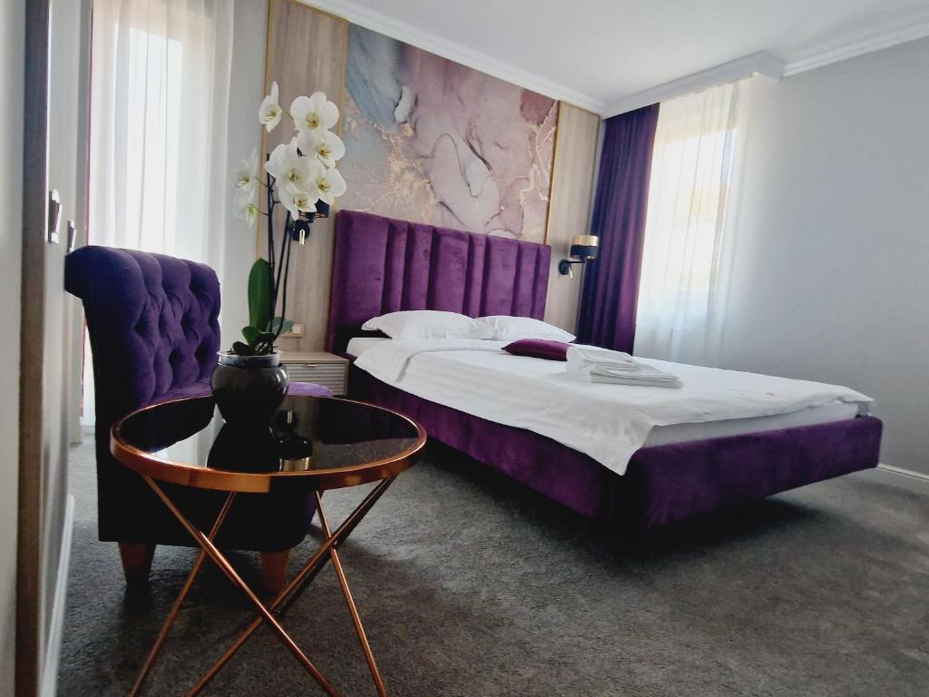 a bedroom with a purple bed and a table at Hotel Casa David in Craiova