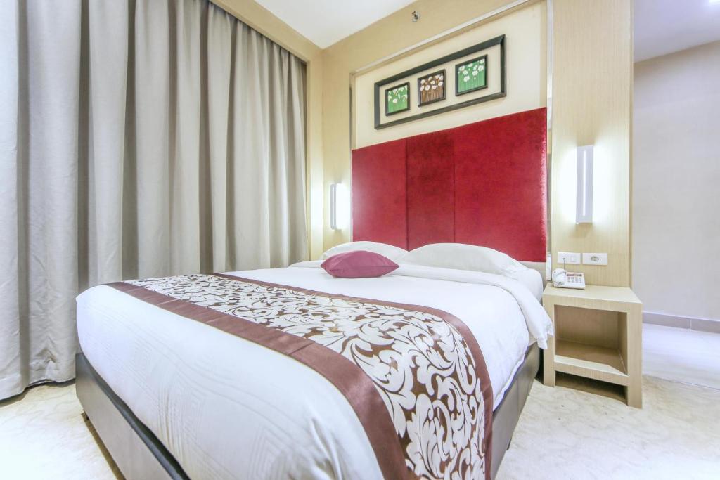 a bedroom with a large bed and a red wall at Batam City Hotel in Nagoya