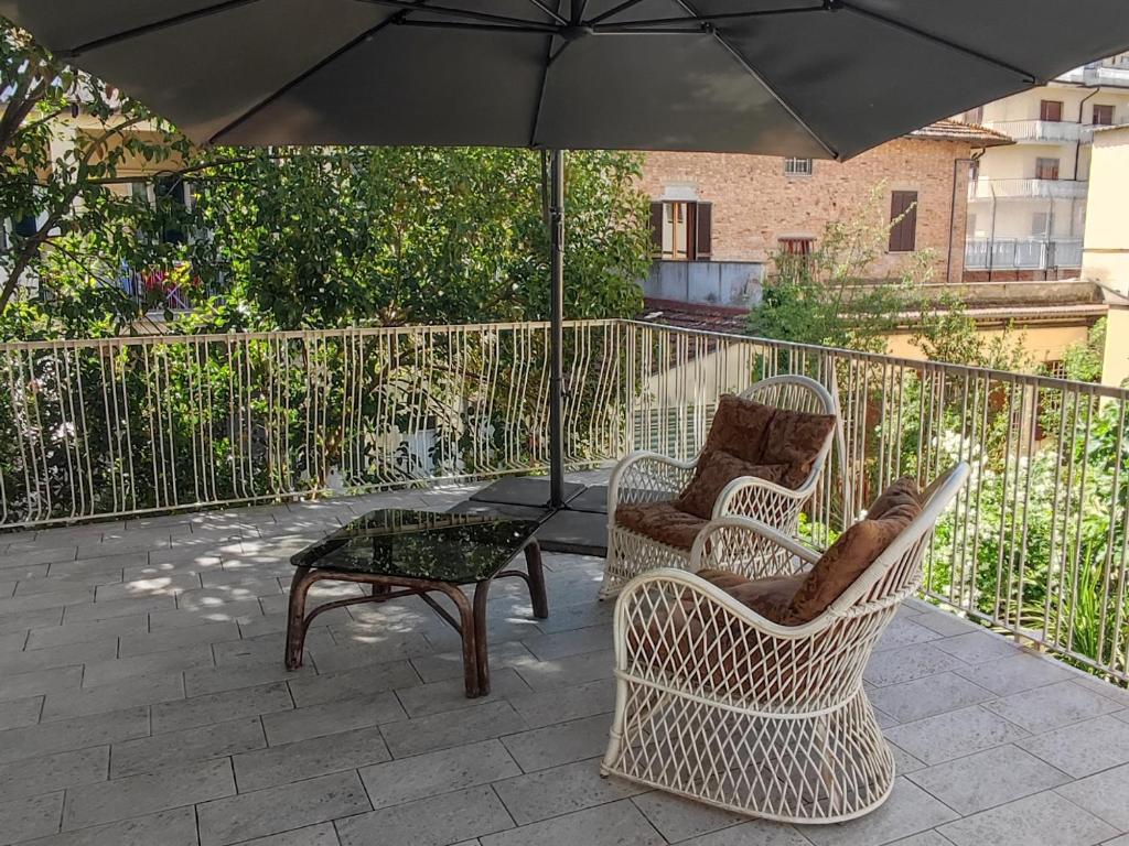 un patio con 2 sillas, una mesa y una sombrilla en La Dimora Di Anna, en Chiusi