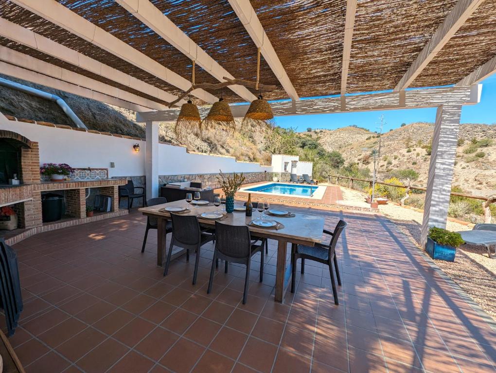 een patio met een tafel en stoelen en een zwembad bij Cortijo Claudia in Taberno