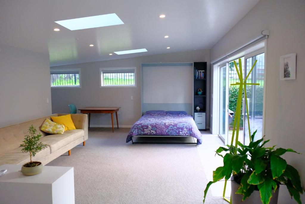 um quarto com uma cama e um sofá em Studio Wing in Saint Heliers em Auckland