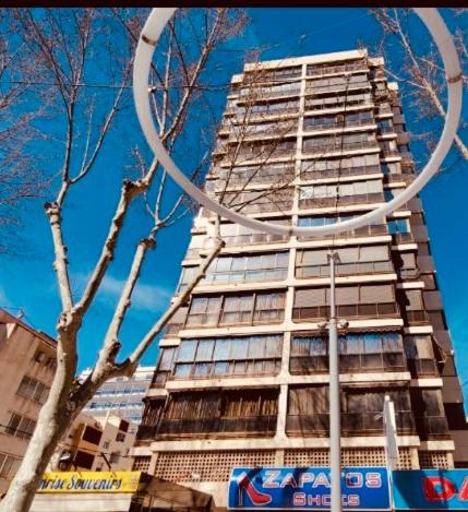 a tall building with a tree in front of it at Apartamento las OLAS playa de levante in Benidorm