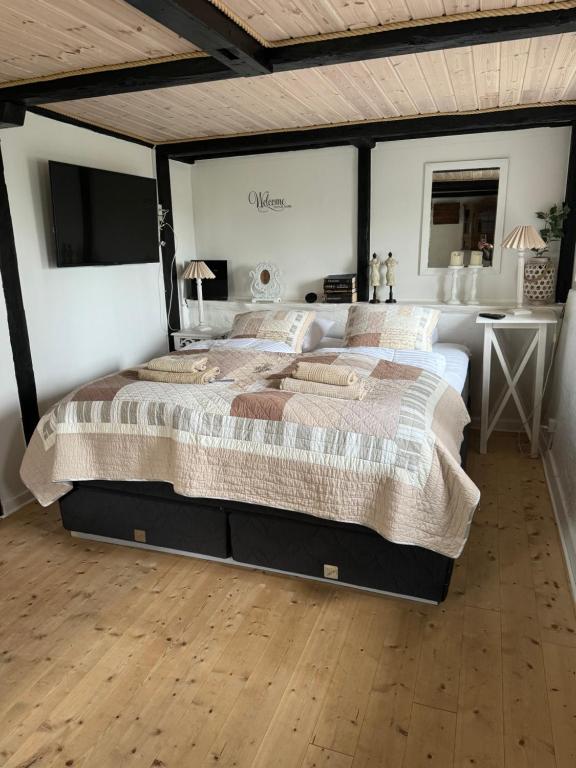 a large bed in a bedroom with a wooden floor at Conedue B&B in Væggerløse