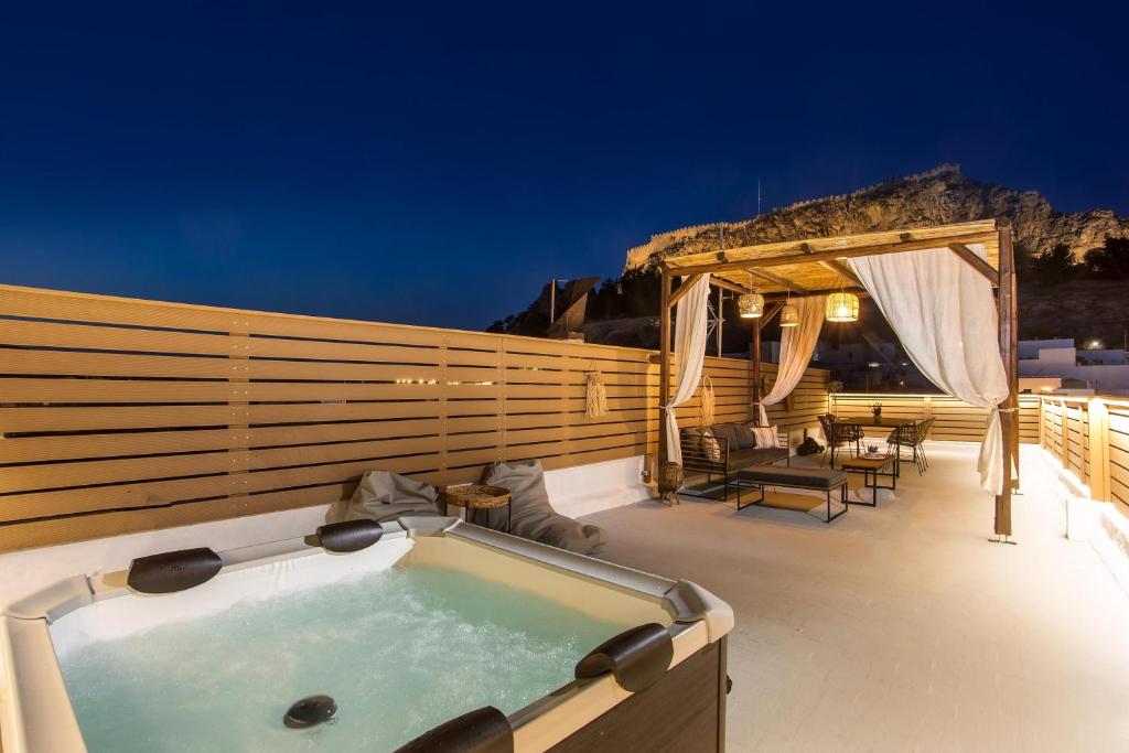 a hot tub on a deck at night at Bliss Luxury Suites in Líndos