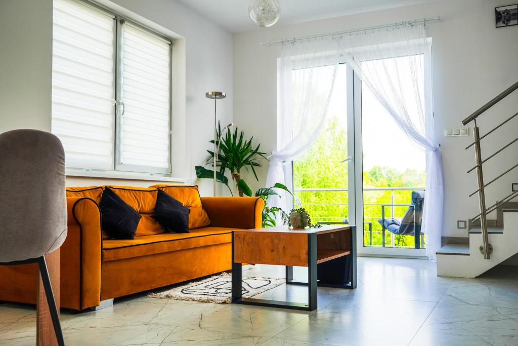 a living room with a orange couch and a table at Dom na Białych Brzóz pod Krakowem in Zabierzów