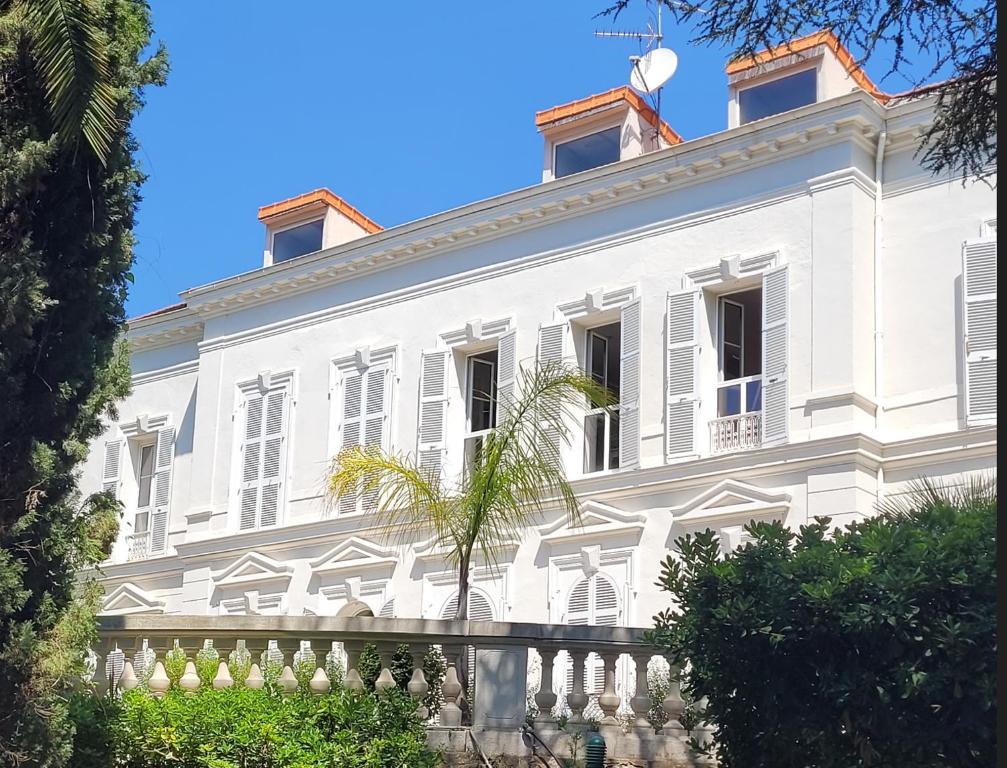 une maison blanche avec un palmier devant dans l'établissement Appartement 3P dans Maison Bourgeoise - 6 personnes - Vue Mer - Parking, à Cannes