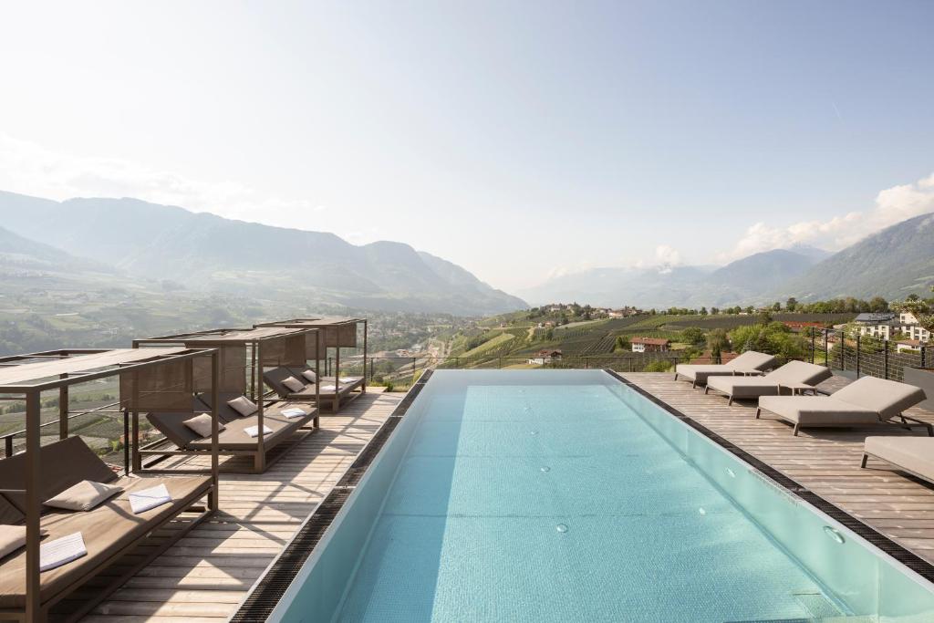 a swimming pool with chairs and a view of mountains at Landsitz Stroblhof in Tirolo