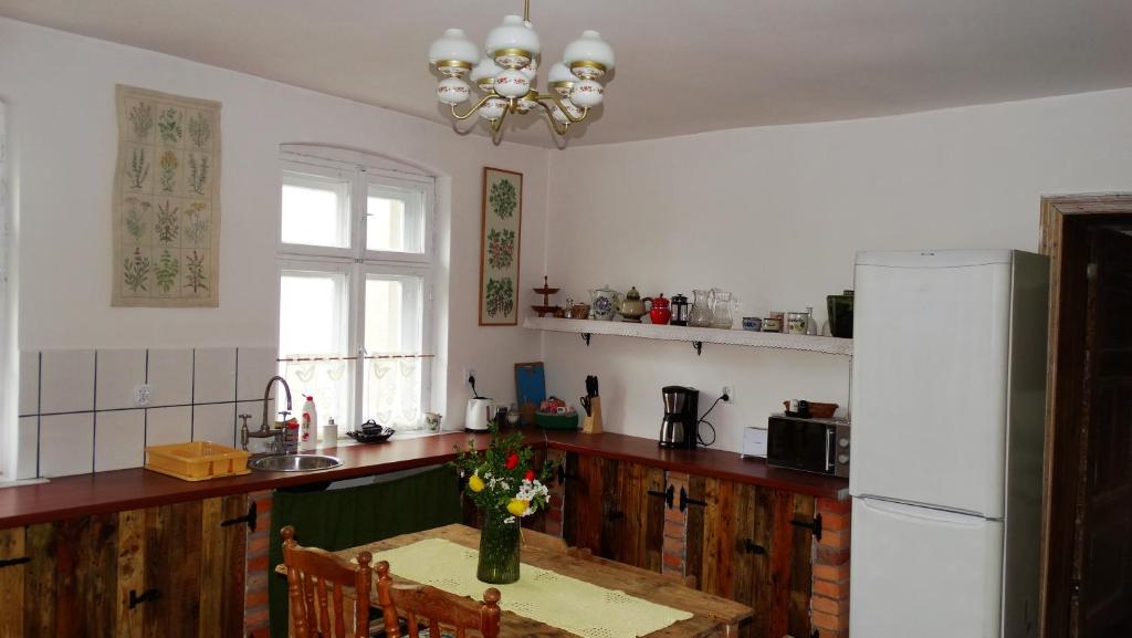 a kitchen with a table and a white refrigerator at Dom na Mazurach Pilec- Apartament in Pilec