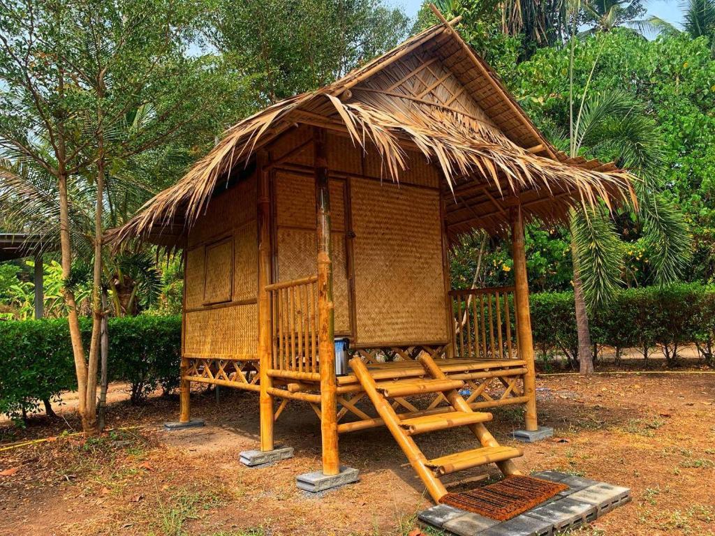 une petite cabane avec un toit de chaume et une échelle dans l'établissement Samui Camping Farm, à Laem Sor