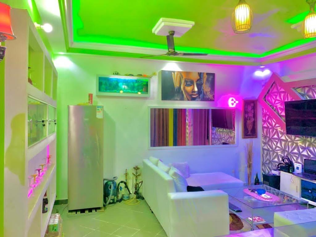 een woonkamer met roze en groene verlichting bij appartementmarcus in Cotonou