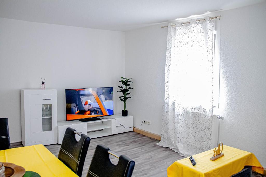 een woonkamer met een tv en een tafel en stoelen bij F&F Suites Ilsfeld - 3 Zimmer OG Apartment - Zentral mit kostenfreien Privatparkplätzen und WLAN in Ilsfeld