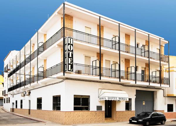 a white building with a black car parked in front of it at Hotel Borja in El Puig