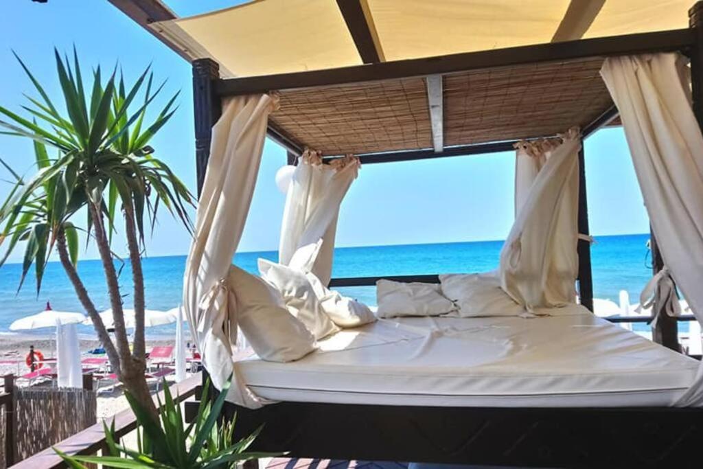 - un lit sur la plage avec l'océan en arrière-plan dans l'établissement Charming #targaflorio apartment, fully equipped, à Campofelice di Roccella