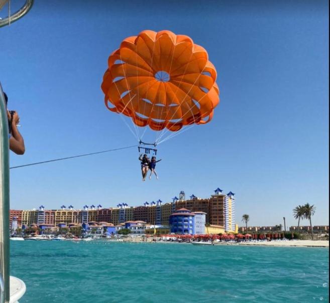 a person on a parachute over the water near a beach at شاليه سي فيو بورتو مارينا عائلات - Porto Marina Sea View in El Alamein