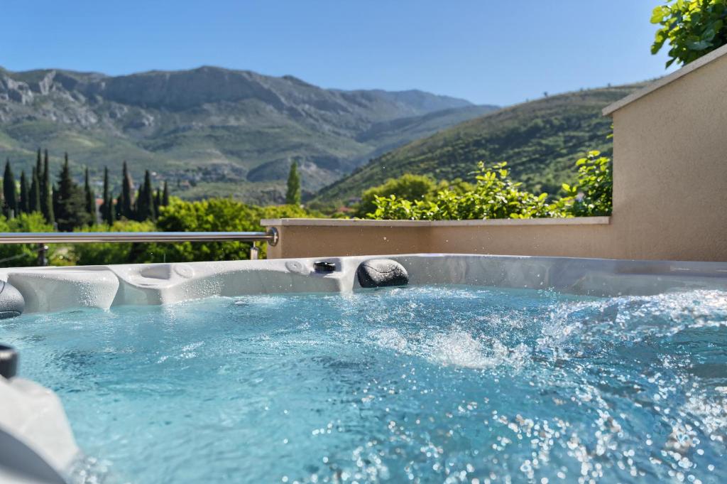 a hot tub with blue water and mountains in the background at RELAX apartment Split area with private jacuzzi on terrace with mountain view in Srinjine