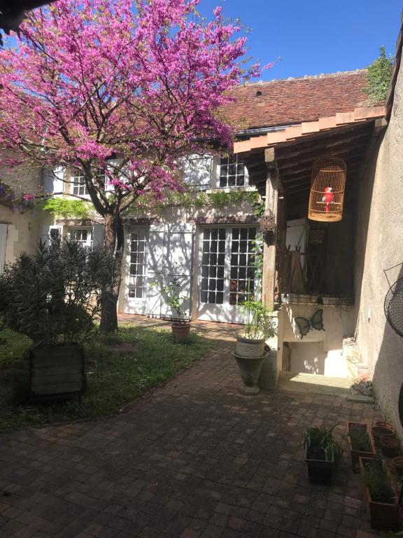 a tree with pink flowers in front of a building at Loggia de la Closerie in Descartes